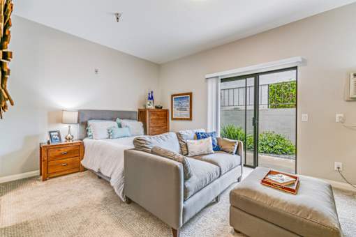 A bedroom with a bed, nightstand, and chair.