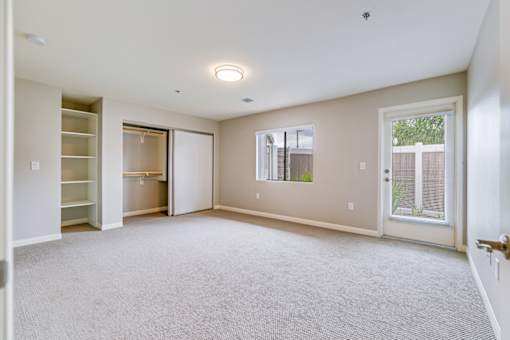 A spacious room with a carpeted floor and a window with blinds.
