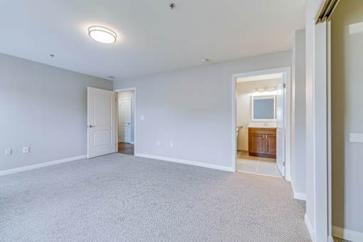 A large empty room with a carpeted floor and a doorway leading to another room.