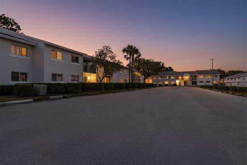 A street view of a residential area with buildings on both sides and a clear sky.