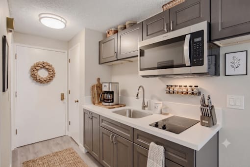 A kitchen with a white counter top and a white sink.
