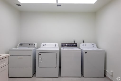 a row of washers and dryers in a laundry room with white appliances