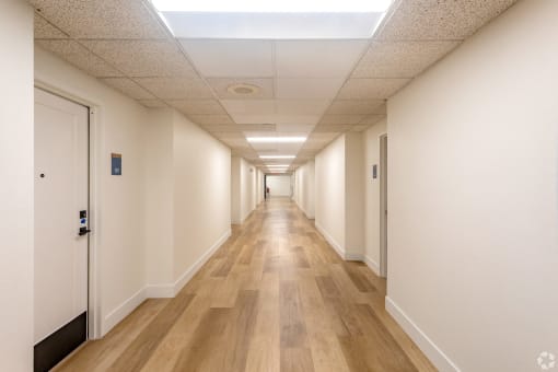 a hallway with white walls and wooden floors and doors