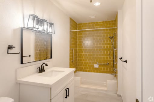 a bathroom with yellow tile and a sink and a shower