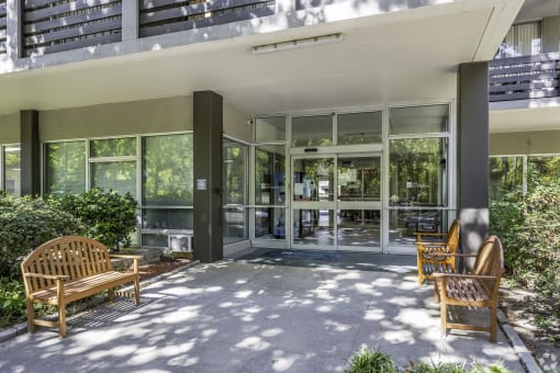 the front porch of a condo building with benches and glass doors