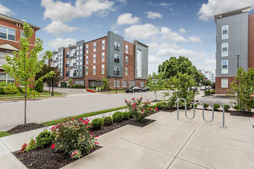 an exterior view of an apartment complex with a sidewalk and trees