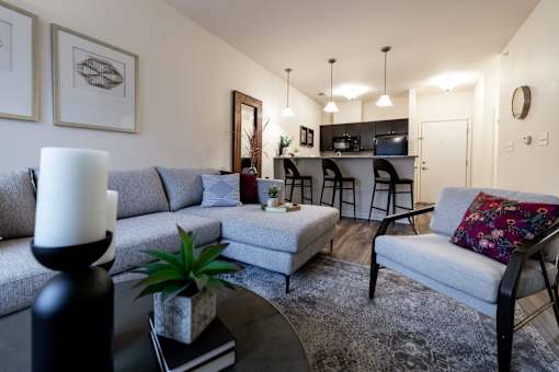 a living room with couches and a table with a kitchen in the background