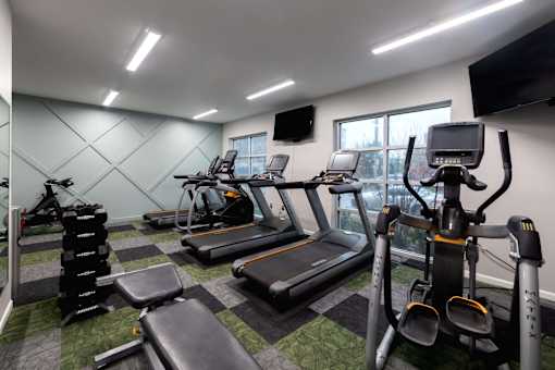 a gym with various cardio equipment and a window