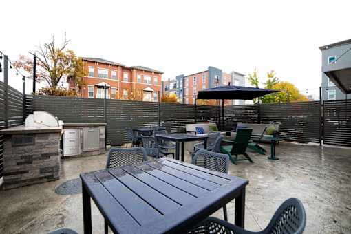 a patio with tables and chairs and a grill