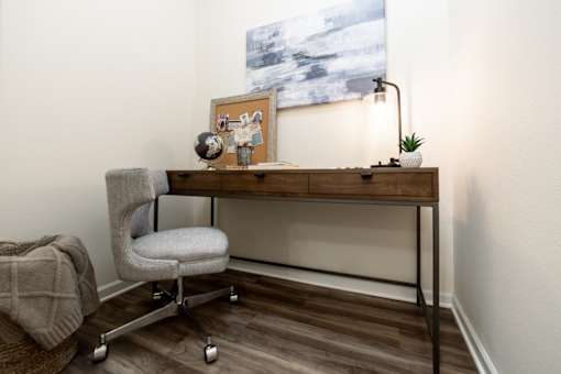 a desk with a chair and a painting on the wall