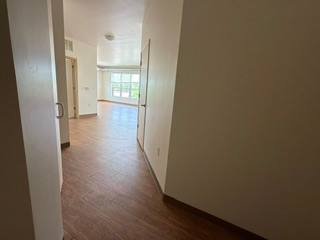 A long hallway with wood floors and white walls.