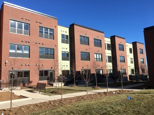 A row of red brick apartment buildings with trees in front.