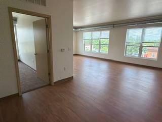 A room with a wooden floor and a doorway leading to another room.