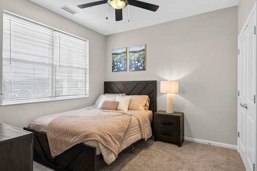 A bedroom with a bed, nightstand, and a ceiling fan.