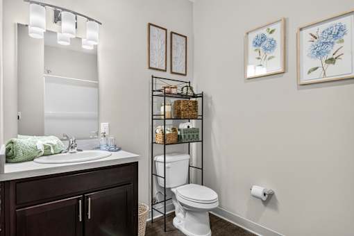 A bathroom with a white toilet and a sink with a green towel on it.