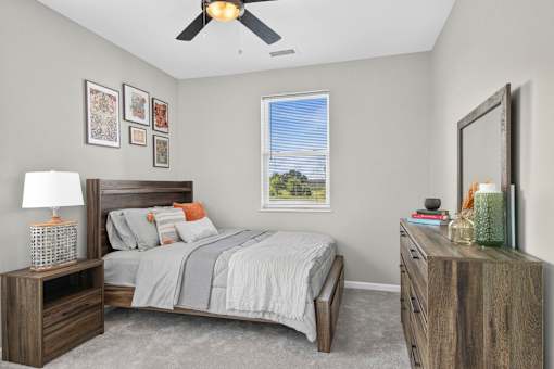 A bedroom with a bed, nightstand, and a window with a view.