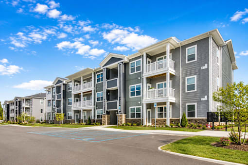 A large apartment complex with a parking lot in front.