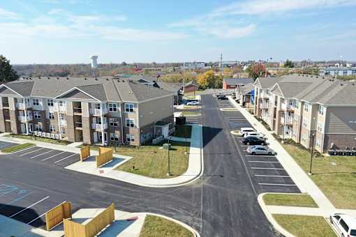 an aerial view of an apartment complex with a parking lot and a street