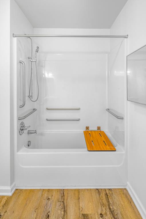 a white bathroom with a shower and a wooden board in the tub