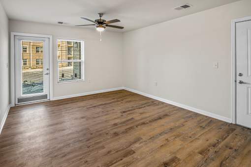 an empty living room with a ceiling fan and a window