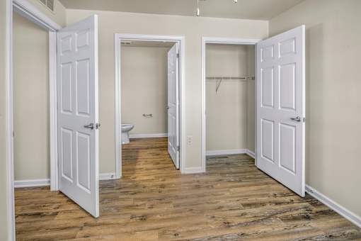 an empty room with three doors and a toilet in the closet