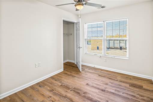 an empty bedroom with a window and a door to a closet