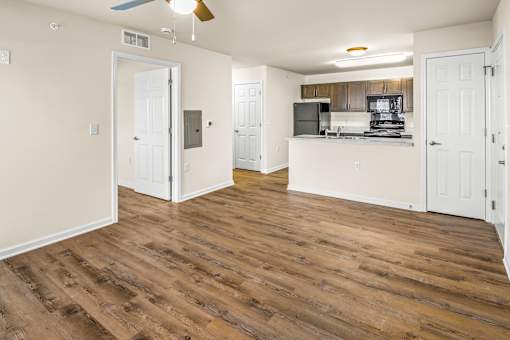 the living room and kitchen of an apartment with wood flooring