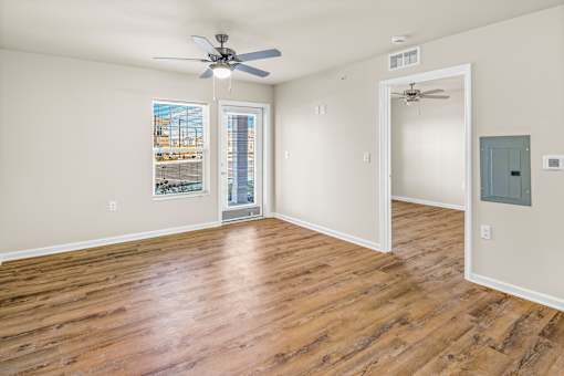 an empty living room with wood floors and a ceiling fan