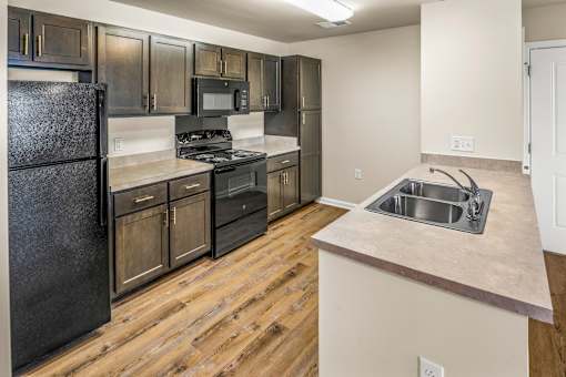 an empty kitchen with wood flooring and stainless steel appliances