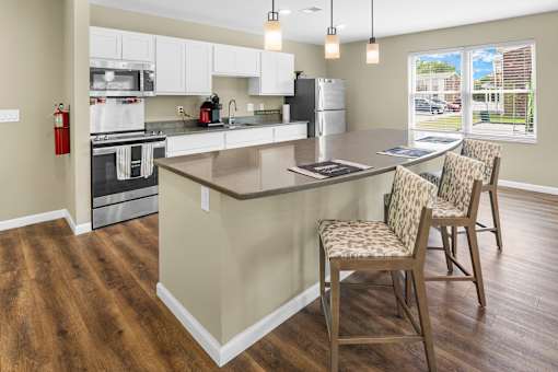 A kitchen with a white counter and brown chairs.