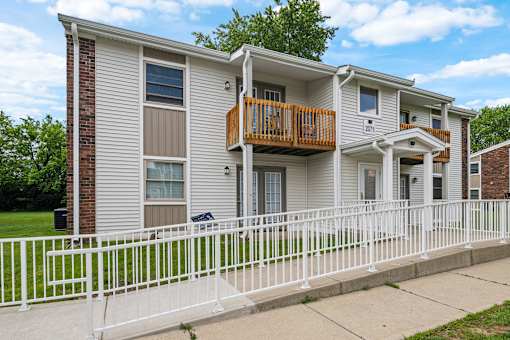 A two-story apartment building with a white fence in front.
