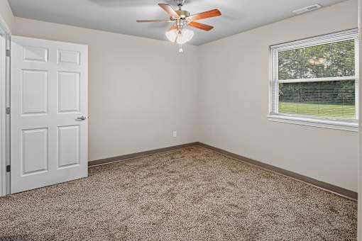 A room with a ceiling fan and a window with blinds.