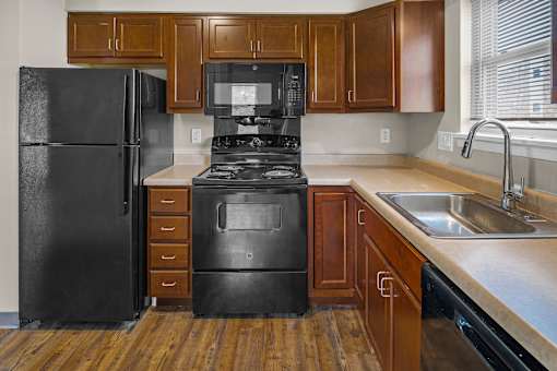 A black refrigerator and stove in a kitchen with wooden cabinets.