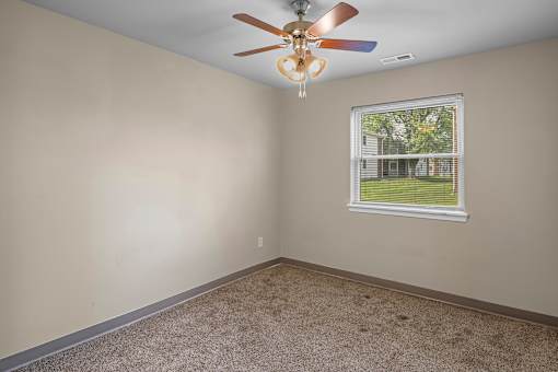 A room with a ceiling fan and a window showing an outdoor view.