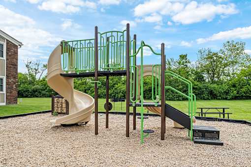 A playground with a green slide and a yellow slide.