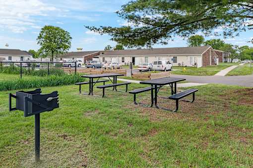 A black mailbox sits on a grassy area next to a picnic table.