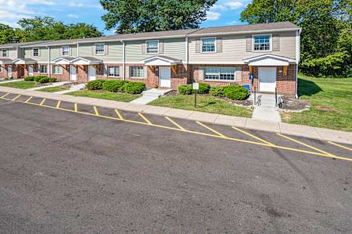 A parking lot in front of a building with a row of houses.