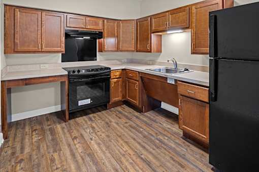 A kitchen with wooden cabinets and a black refrigerator.