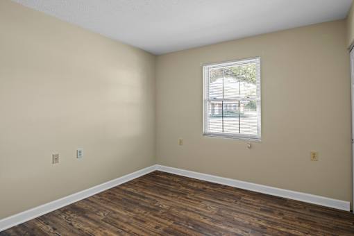 A room with a window and wooden flooring.