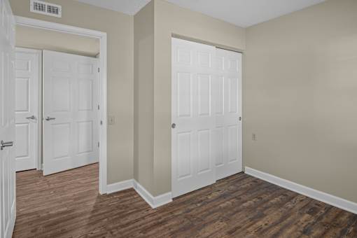 A room with a white door and a brown floor.