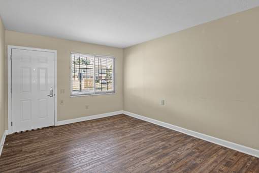 A room with a white door and wooden flooring.