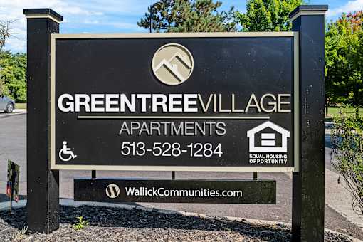 A sign for Green Tree Village Apartments with a website listed below.