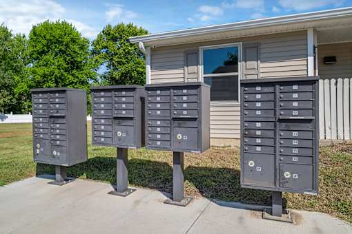 A set of four mailboxes are lined up on a sidewalk.