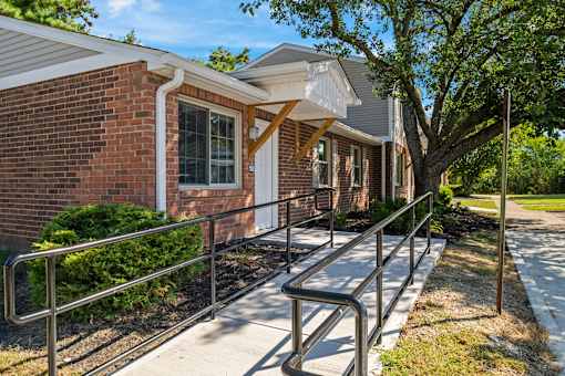 A brick building with a white awning and a metal railing on the sidewalk.