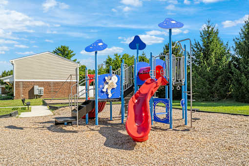 A playground with a red slide and blue umbrellas.