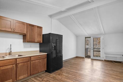 A kitchen with wooden cabinets and a black refrigerator.
