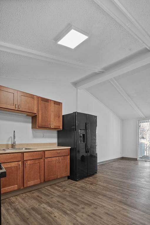 A kitchen with wooden cabinets and a black fridge.