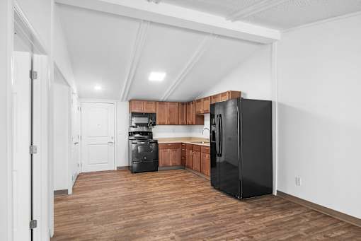 A kitchen with a black refrigerator and wooden cabinets.