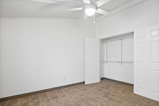 A room with a ceiling fan and carpeted floor.