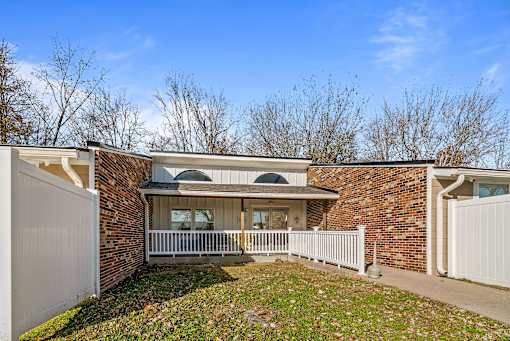 A house with a white fence and a brick wall.